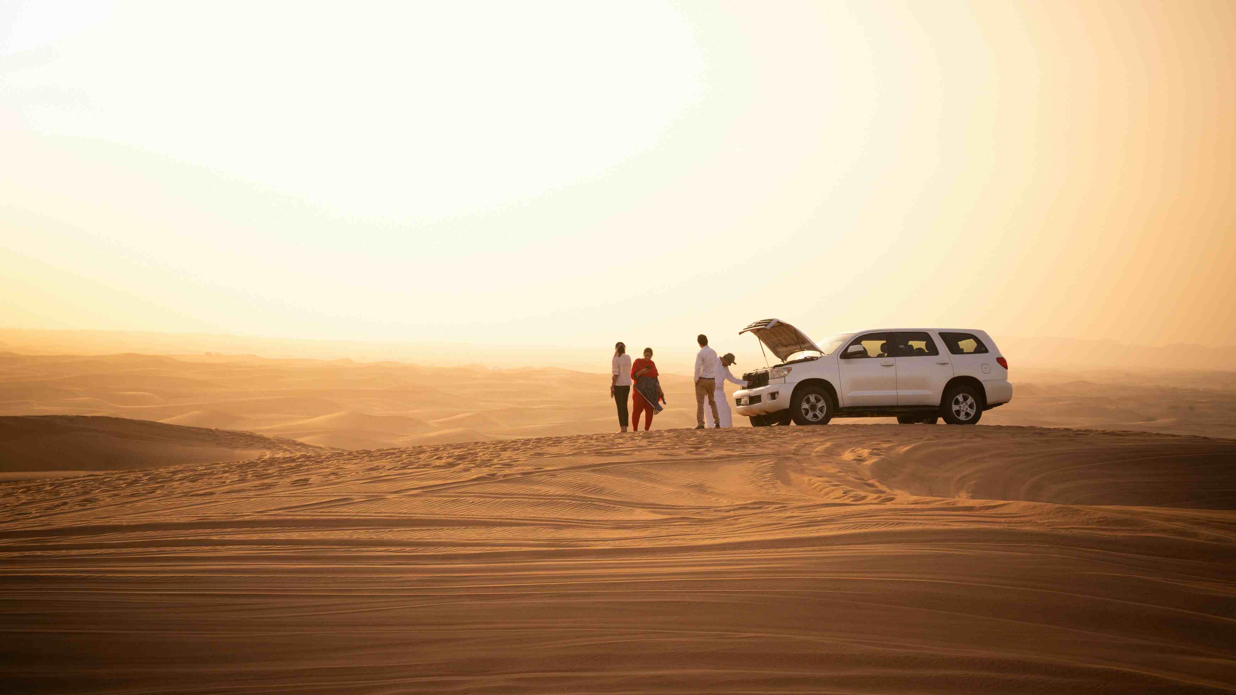 Vehicle cresting a high dune at sunset